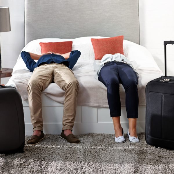 Indoor shot of mature couple lying on bed with luggage